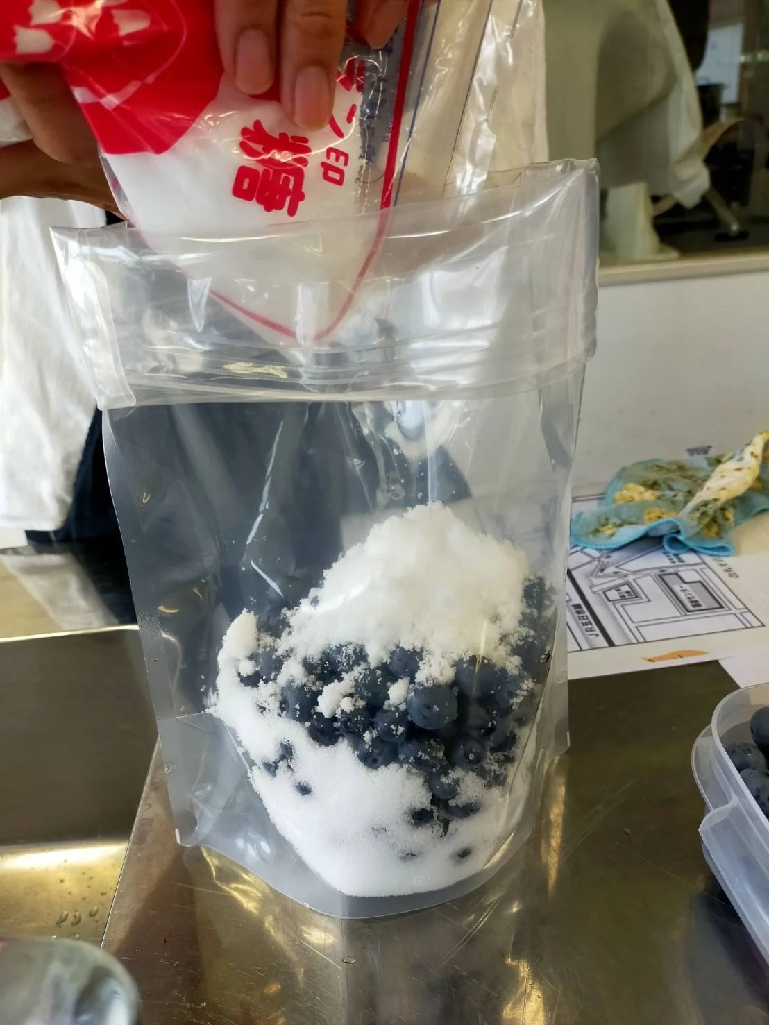 ブルーベリーと砂糖を透明な袋に重ねている手元